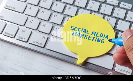 Social Media Marketing Strategy Concept with Hand Writing on Speech Bubble Note Pad and Computer Keyboard Stock Photo