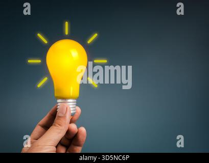 Hand holding glowing yellow light bulb symbolizes creative idea, innovation, inspiration, brainstorming, solution concept, startup thinking, and brigh Stock Photo