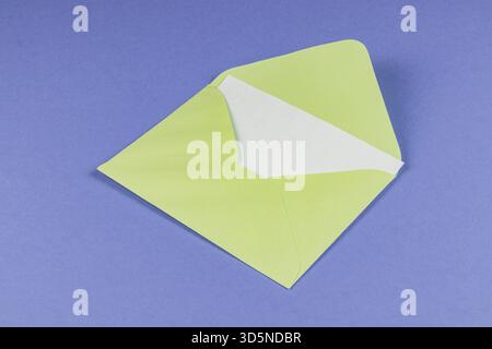 A simple green envelope sits on a blue surface with its triangular flap open, showing white inside. It is a clean and minimalist design that catches t Stock Photo