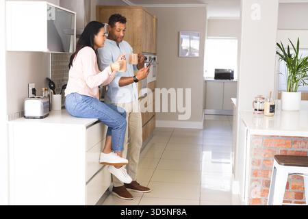 Sharing morning coffee in modern kitchen, couple having relaxed conversation Stock Photo
