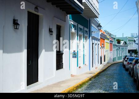 A narrow cobblestone street is lined with colorful buildings, each featuring unique doors and windows. Stock Photo
