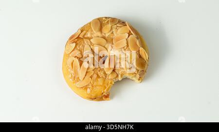 donut with almond topping with bitten edges on a white background Stock Photo