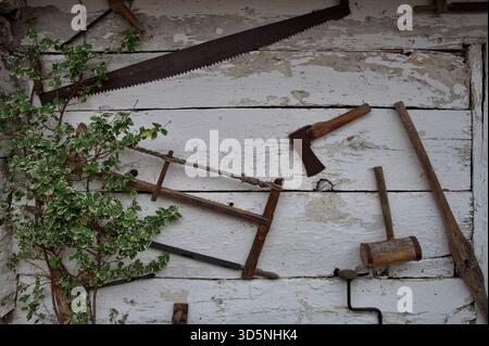 Old tools on the wooden cottage wall Stock Photo