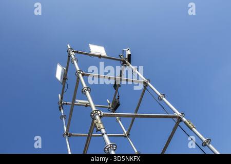 Looking up at metal tower and communication antenna against clear blue sky. modern industrial construction and technology framework symbolizing connec Stock Photo