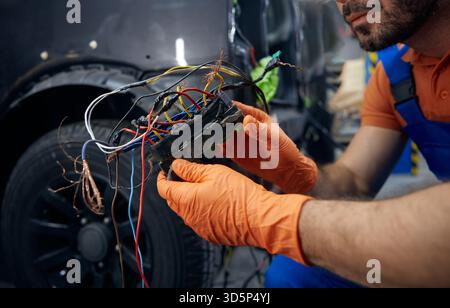 Mechanic inspecting complex car wiring harness in garage Stock Photo