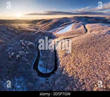 An aerial drone view of a snow - covered forest on a hill in the sunrise in Slovakia Stock Photo