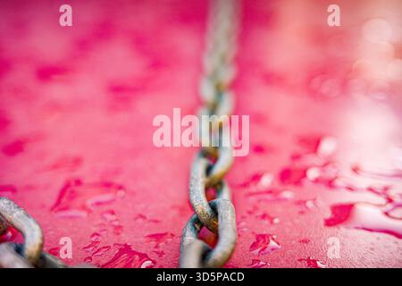 Diagonal metal chain on wet pink background Stock Photo