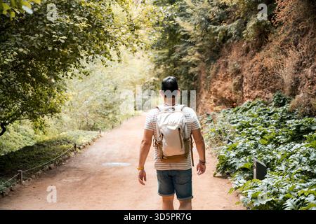 Man walking alone on forest trail with backpack and shorts Stock Photo