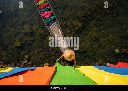 Aerial view of vibrant colored textiles spread across a boat on Inle Lake, contrasting with the dark water, creating a mesmerizing pattern, Inle Lake, Stock Photo
