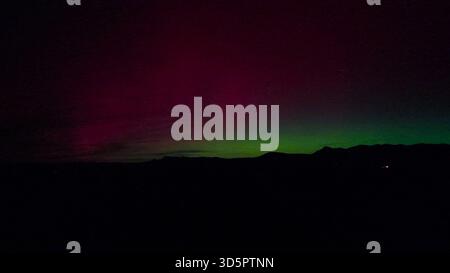 View of the aurora borealis illuminating the night sky above a dark ...