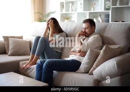 Sad couple complaining after argument sitting on a couch at home Stock Photo