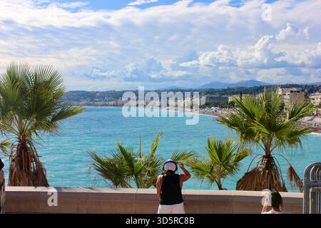 Panoramic view of the turquoise coastline and palm trees along the Promenade des Anglais in Nice, France, on a bright sunny day. Stock Photo