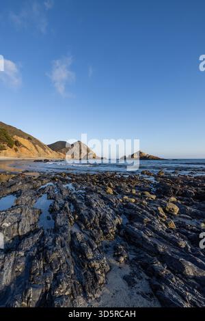 Layered rocky shoreline and coastal cliffs at low tide on Pfeiffer Beach, Big Sur, California. Stock Photo