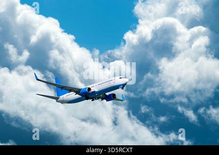 Airplane in the flight, travel background with airplane flying in the blue sky high above the ground Stock Photo