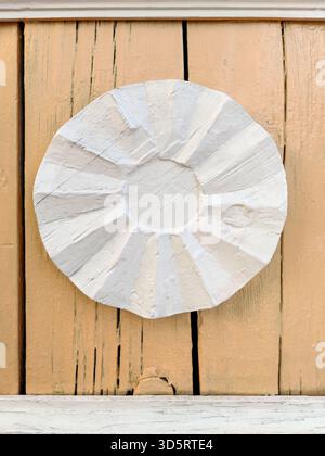 Antique white round decoration on old wooden wall painted with beige color. Copy space. Close-up. Stock Photo