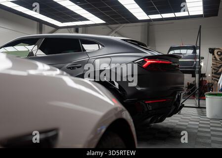 Matte black Lamborghini Urus in premium workshop with luxury cars Stock Photo