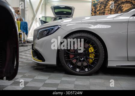 Mercedes Benz AMG front quarter in workshop with yellow calipers Stock Photo