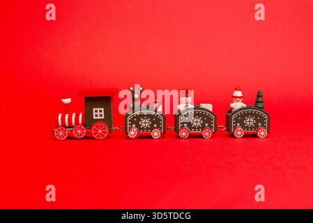 Wooden Christmas train toy with tiny festive characters displayed on a bright red background Stock Photo