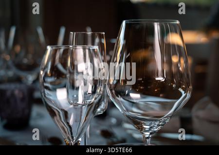 Three wine glasses are on a table, with one of them being a wine glass. The other two glasses are also clear and have a similar shape. The table setti Stock Photo