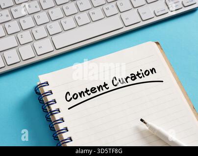Notepad with content curation handwritten, keyboard, and pen on blue background represent organizing and presenting online information Stock Photo