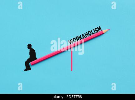 Silhouette of a businessman balancing on a pink pencil seesaw with the word workaholism written on it, representing work-life balance challenges Stock Photo