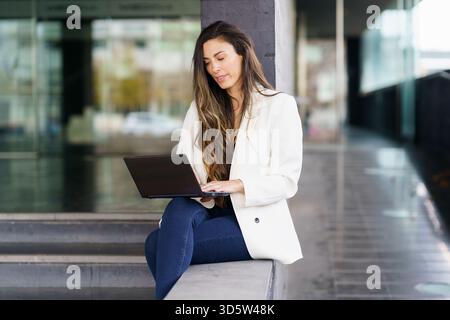 A young professional woman works on her laptop outdoors, highlighting her careerdriven mindset Stock Photo
