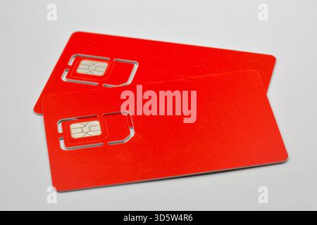 Two red SIM cards with chip and logo closeup on white. Mobile network operator prepaid cards showing standard and micro SIM formats for cellular commu Stock Photo