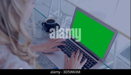 Typing adult female working on green-screen laptop at glass table with black coffee, copy space Stock Photo