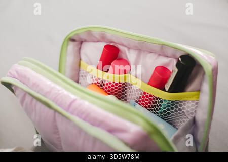 Make-up supplies placed in a small cosmetics pouch, isolated on white background Stock Photo