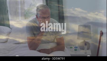 Sitting elderly man resting head, gazing on bed in striped polo, with pills, cane, cloud overlay Stock Photo