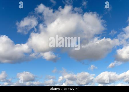 White cumulus clouds drifting across a blue sky Stock Photo