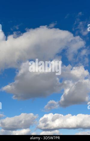 White cumulus clouds drifting across a blue sky Stock Photo