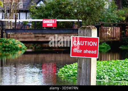 A large red warning danger sign in the River Wey navigation canal warning boaters of a small weir on a sunny autumn day Weybridge Surrey England UK Stock Photo