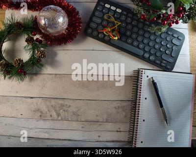 Festive Holiday Workspace Decor - Cozy Christmas office desk with keyboard, notebook, and festive decor on rustic wood. Ideal flat lay for holiday wor Stock Photo
