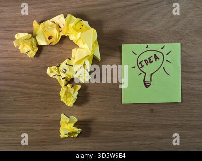 From Question to Bright Idea - A question mark made of crumpled yellow paper next to a green sticky note with a lightbulb drawing and "IDEA". Problem- Stock Photo