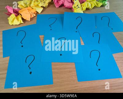Unanswered Questions & Crumpled Ideas - Blue papers with question marks and colorful crumpled paper symbolize problems, confusion, brainstorming, and Stock Photo