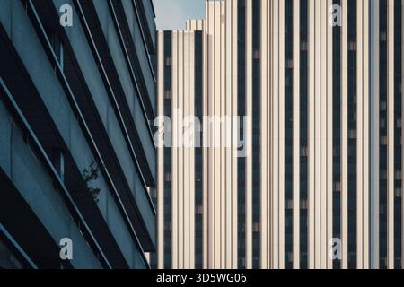 Abstract architectural photography showing geometric contrast between diagonal glass facade and vertical building lines in blue-gray and beige tones Stock Photo