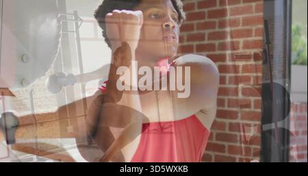 Training adult male in red athletic tank top stretching at gym, with barbell and ballet barre Stock Photo