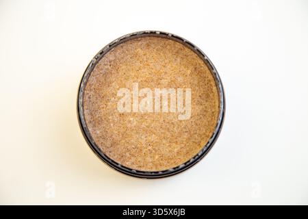 Black round container features a brown textured substance, highlighting smoothness and subtle Stock Photo