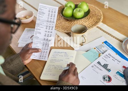 Mature Black Man Reviewing Utility Bills and Calculating Household Expenses Stock Photo