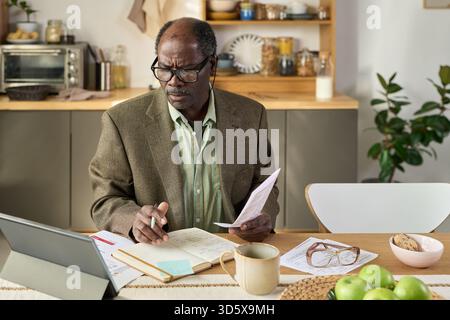 Senior Black Man Analyzing Financial Documents While Working Remotely at Home Stock Photo
