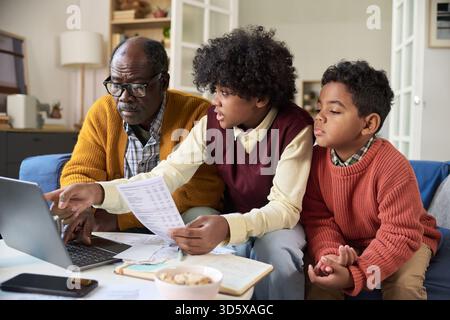 Mature Black Man and Two Boys Analyzing Financial Documents Together Stock Photo