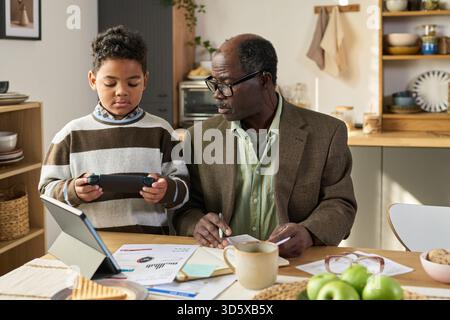 Mature Black Man Teaching Black Boy Using Digital Tablet Stock Photo