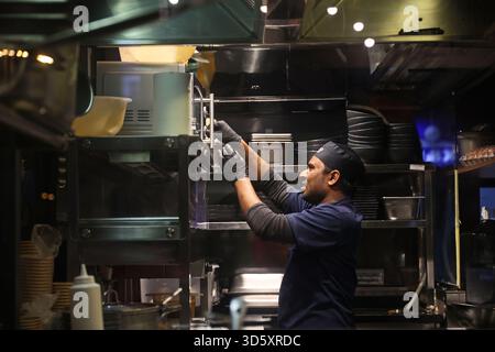 Chef preparing food in the kitchen of an Indian street food restaurant in Budapest, Hungary Stock Photo