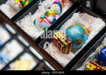 Close-up of a collection of colorful, intricately detailed glass Christmas ornaments on black stands, contrasting against a dark background Stock Photo