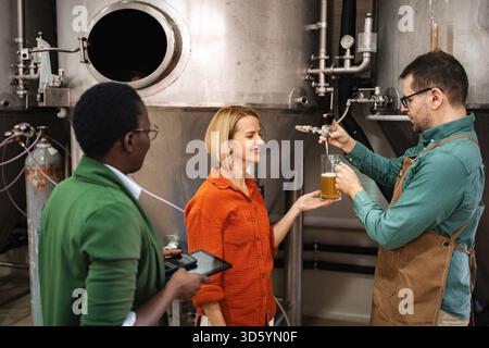 Brewer pouring craft beer for tasting in a modern brewery Stock Photo