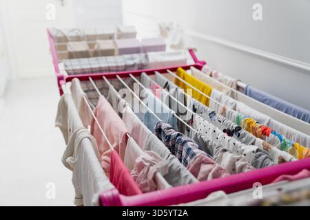 Fresh laundry spread across several drying lines on an indoor rack captured from above, emphasizing fabric patterns, color pins, and the organized str Stock Photo