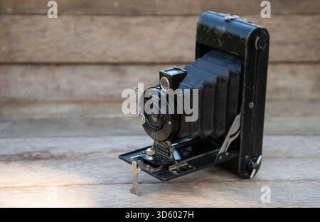 Close-up of a classic Ensign folding camera with bellows, displayed on a rustic wooden surface. Ideal for themes of photography history and vintage te Stock Photo