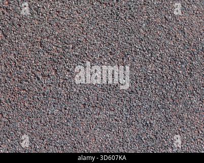 A full frame closeup of fine grained asphalt tarmac or gravel aggregate creating a detailed and rough texture background Stock Photo