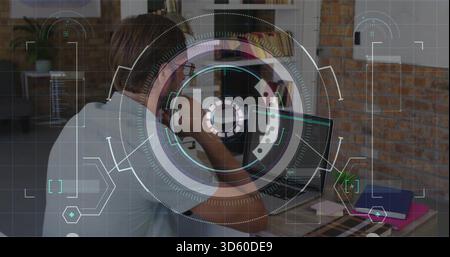 Talking man holding smartphone to ear in office, wearing light shirt and headset with laptop HUD Stock Photo
